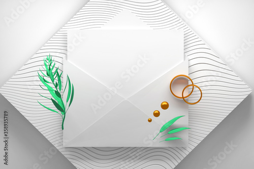 Opened paper envelope with blank card and plant branch with golden wedding engagement rings, plant branch and golden spheres photo