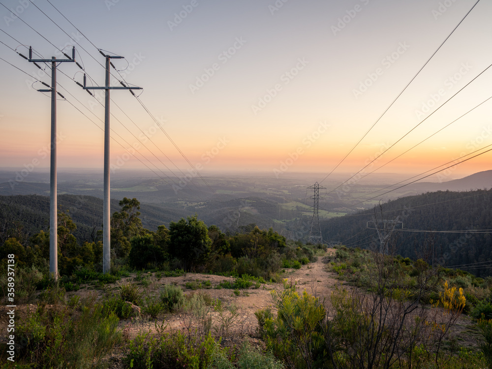 Powerlines on a hill at sunset