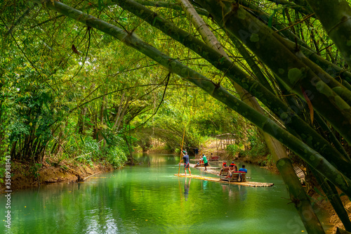 Falmouth, Jamaica. Tourists on bamboo raft rides on Martha Brae River. Relaxing scenic tour through countryside landscape under canopy of trees. People enjoy summer vacation activity.