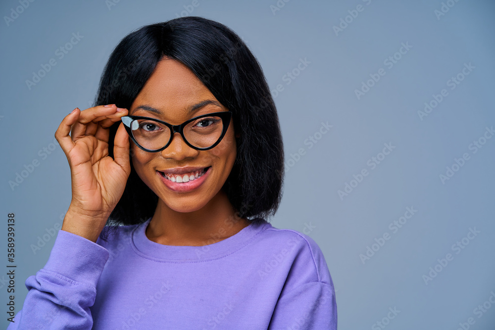 Smiling girl is posing, looking at the camera, corrects her glasses. Emotions concept Smiling girl is posing, looking at the camera, corrects her glasses. Emotions concept