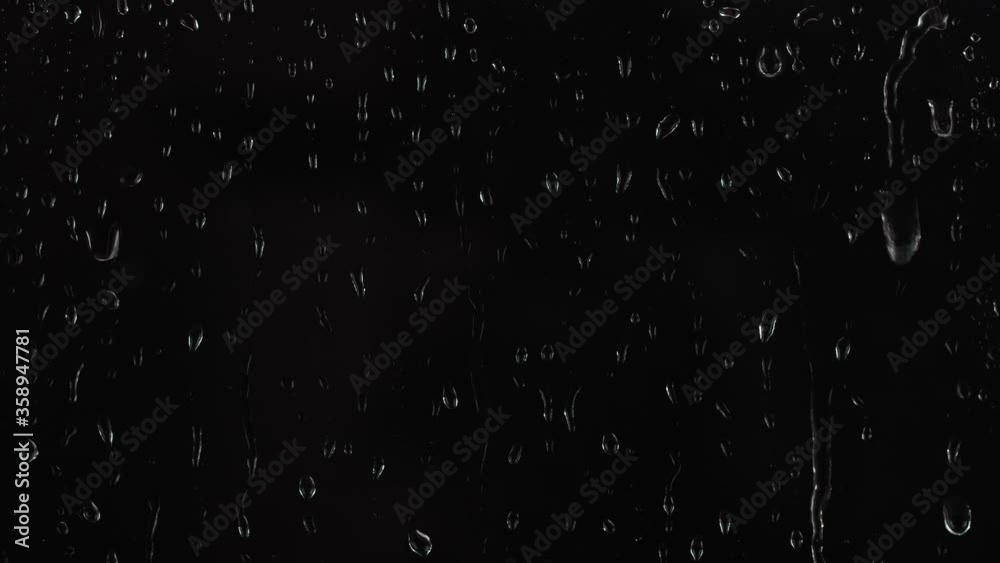 4K footage of rain drops falling on window glass on black background.