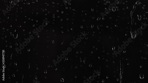 4K footage of rain drops falling on window glass on black background. photo