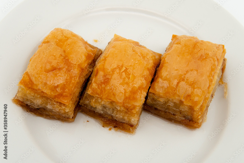 three slices of Turkish baklava on a white plate, close up three slices of Turkish baklava on a white plate, close up