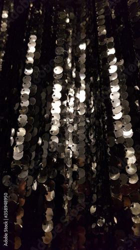 Rows of shining surface with silver sequins on blurred black background