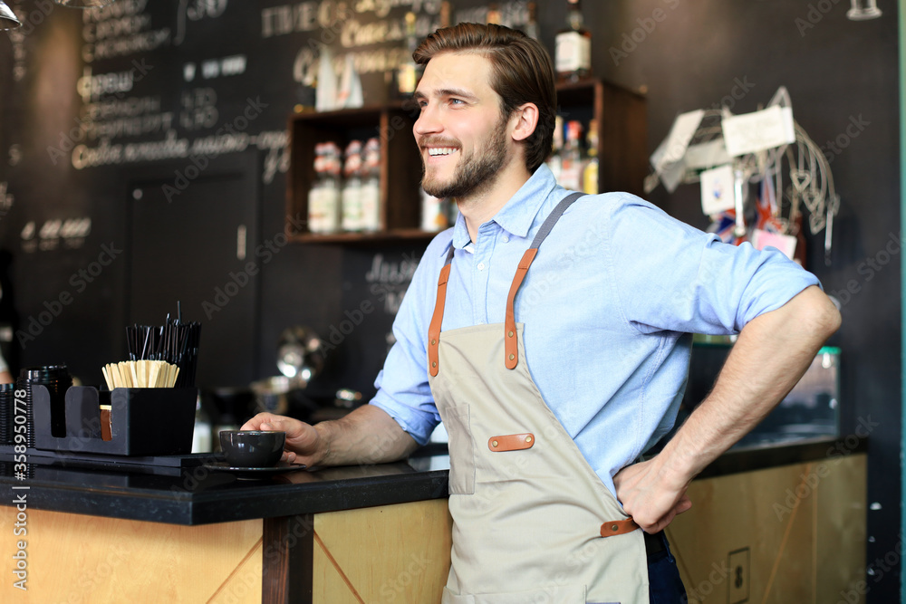 Shot of happy young bar owner standing near the counter and looking away smiling. Shot of happy young bar owner standing near the counter and looking away smiling.