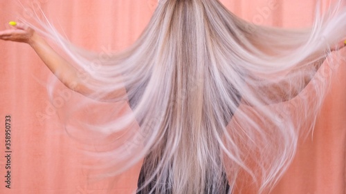 Beautiful blond woman throws her long wavy hair. Hair care concept.