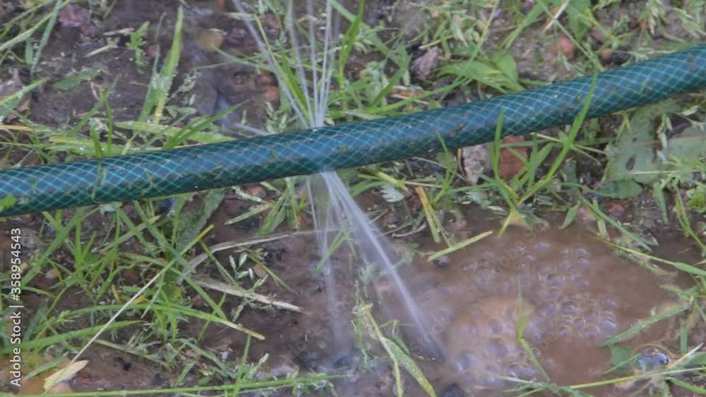 the leaky pipe from which flows under the pressure of the water puddle the leaky pipe from which flows under the pressure of the water puddle