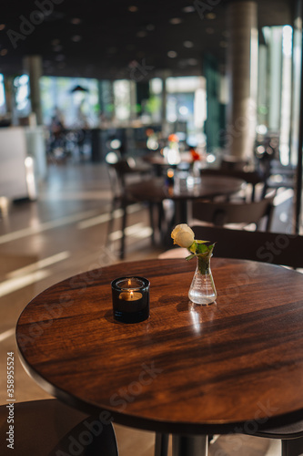 Indoor restaurant interior with small red flowers inside glass flower pot on the wooden table with natural light reflections from windows in Oslo Public library, Norway at Deichman library photo