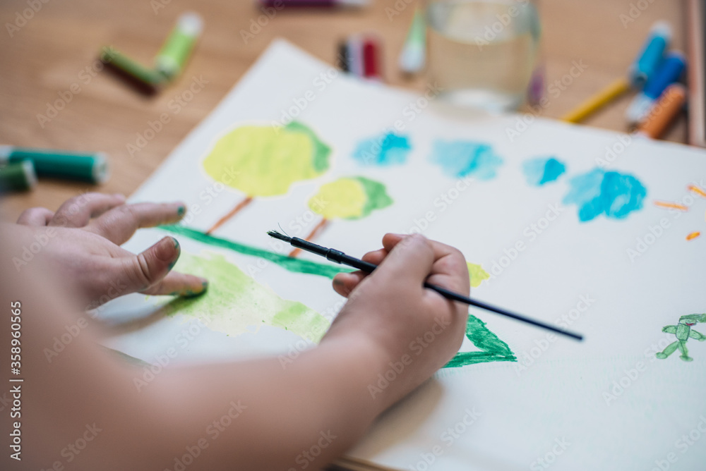 child's hand drawing clouds with a watercolour brush at home child's hand drawing clouds with a watercolour brush at home