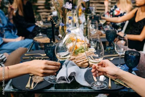 Sticker Women raising glasses with white wine at a garden party with friends and family, outdoors