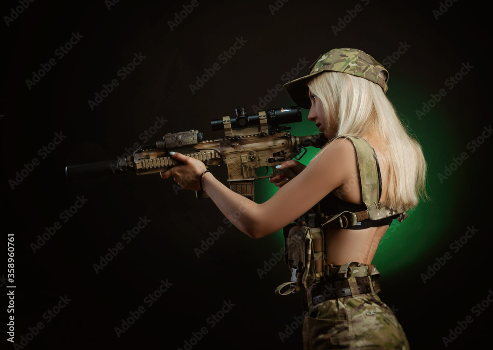 a sexy girl in military airsoft overalls poses with a gun in her hands on a  dark background Stock-Foto | Adobe Stock