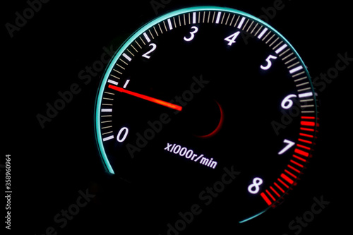 car tachometer with red arrow on black background