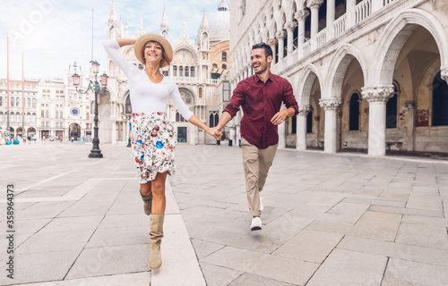 Romantic couple in love running in the city of Venice, Italy. Man and woman at vacation in Italy enjoying time together.