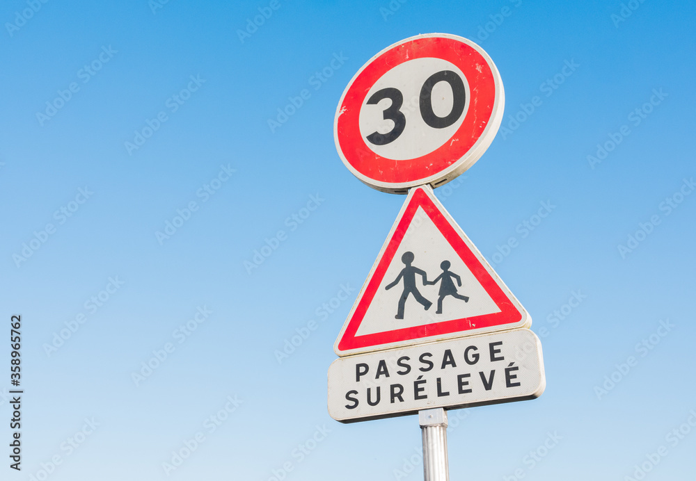 Round 30 kilometers per hour speed limit road sign in a children school area. Written in french Round 30 kilometers per hour speed limit road sign in a children school area. Written in french