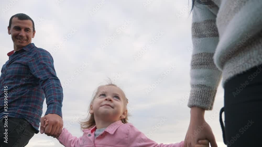 A happy family walks in the Park under the rays of the sun at sunset. Mom, dad and baby holding hands walk in the fresh air, lead a healthy lifestyle. A happy family walks in the Park under the rays of the sun at sunset. Mom, dad and baby holding hands walk in the fresh air, lead a healthy lifestyle.