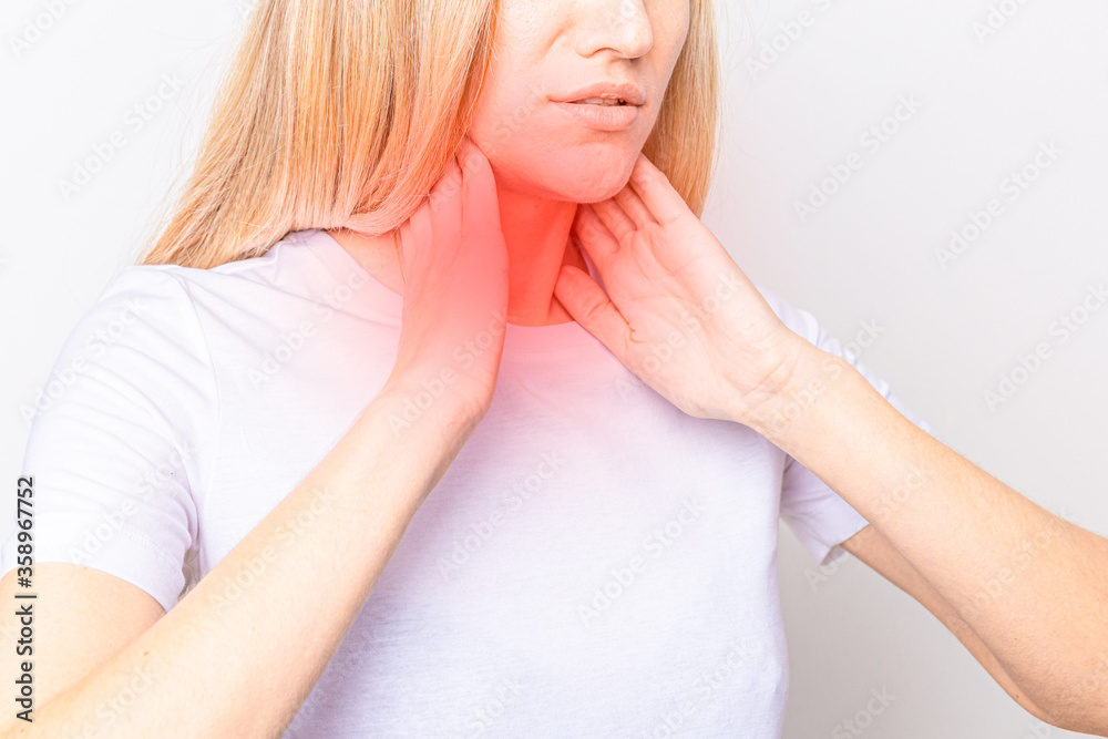Female checking thyroid gland by herself. Close up of woman in white t- shirt touching neck with red spot. Thyroid disorder includes goiter, hyperthyroid, hypothyroid, tumor or cancer. Health care Female checking thyroid gland by herself. Close up of woman in white t- shirt touching neck with red spot. Thyroid disorder includes goiter, hyperthyroid, hypothyroid, tumor or cancer. Health care