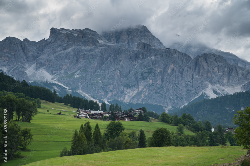 Hotels in Cortina d'Ampezzo, buildings in front of high, dramatic mountains during dramatic weather.