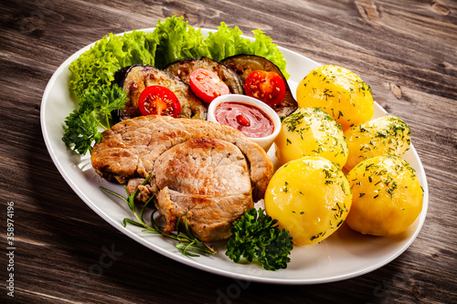 Barbecue beef steak fried potatoes and vegetables on wooden table
