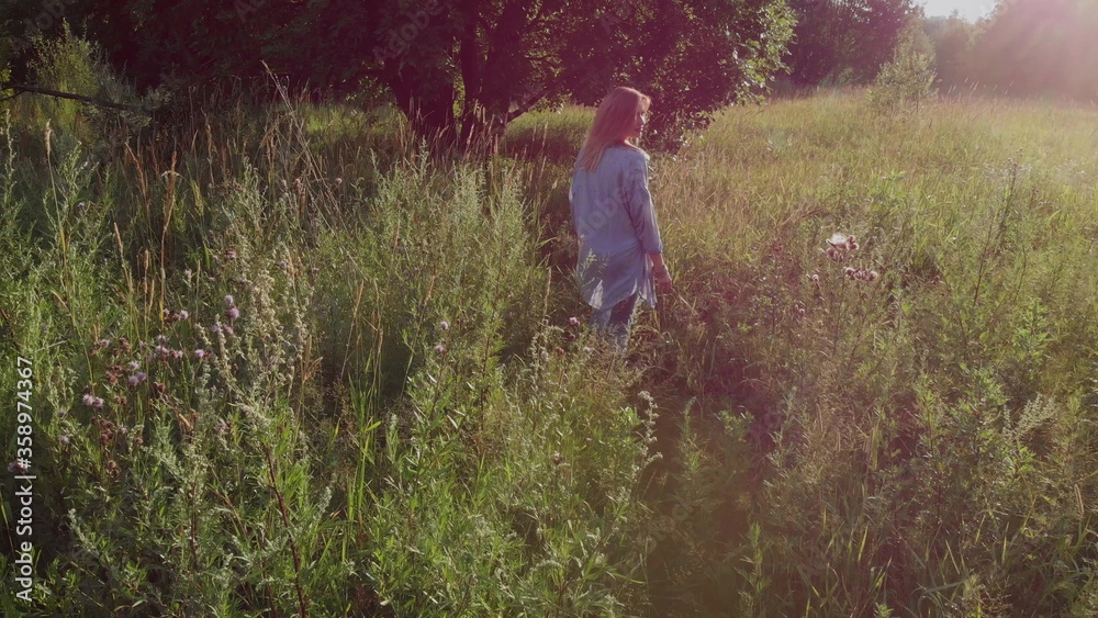 young woman walks and enjoys nature, a Girl in jeans walks in the tall grass,
