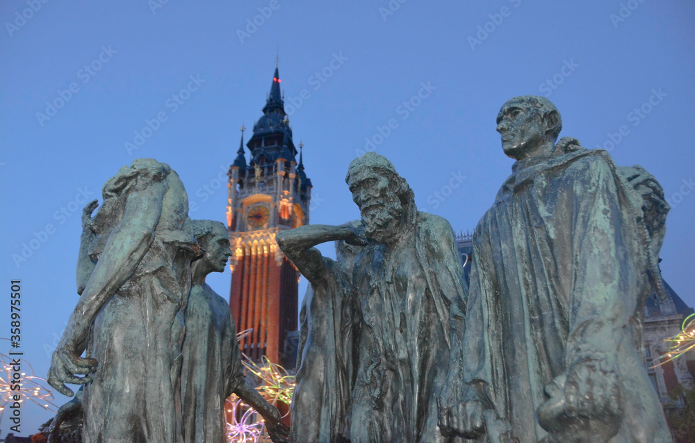 Calais, France, Europe, August 2019. Night view of the town hall building (Le Beffroi de l'Hôtel de Ville) and the stature of the Burgeses de Calais