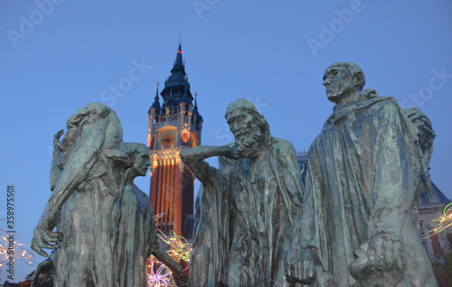 Obraz na płótnie Calais, France, Europe, August 2019. Night view of the town hall building (Le Beffroi de l'Hôtel de Ville) and the stature of the Burgeses de Calais w salonie