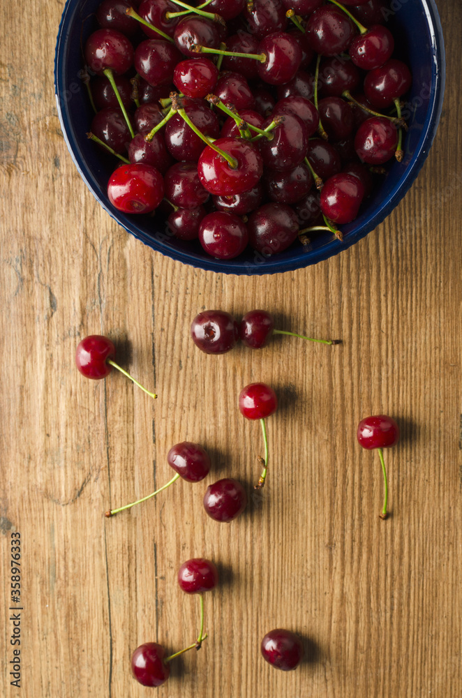 Top view of cherries and bowl on the wooden kitchen table