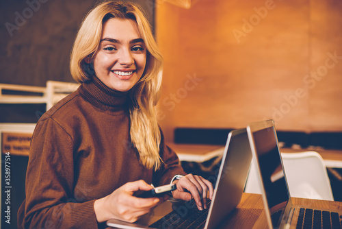 Portrait of cheerful young woman connecting to wireless internet on digital devices for working remotely in cafe, smiling cute female student using laptop computer for learning online on courses .