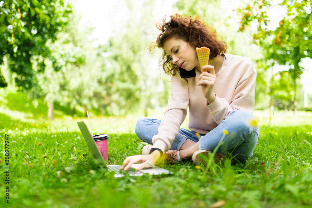 freelance concept. charming girl performs work on a laptop while sitting on the grass in the park freelance concept. charming girl performs work on a laptop while sitting on the grass in the park