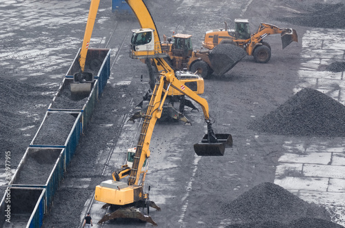 EXCAVATORS AND WHEEL LOADER - Machines at reloading work on a coal yard in rainy weather