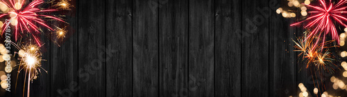Festive Silvester Party background banner panorama long- Red golden firework and bokeh lights on dark black grey wooden wall texture, with space for text