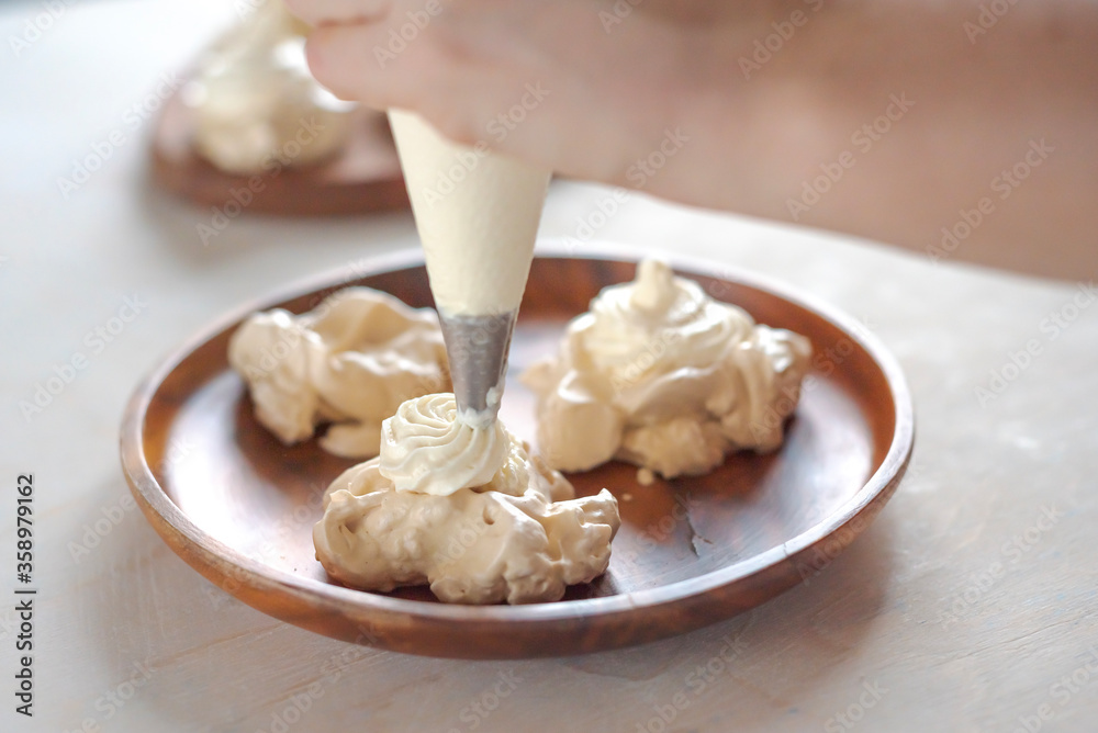 the process of creating Pavlova dessert, decorating the meringue with cream from the culinary bag the process of creating Pavlova dessert, decorating the meringue with cream from the culinary bag