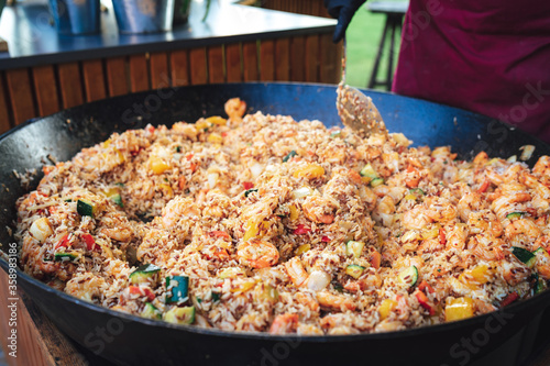 Big black pan full of meal. Mix of rice, vegetable and seafood - probably Paella. Celebration, party, birthday or wedding concept.