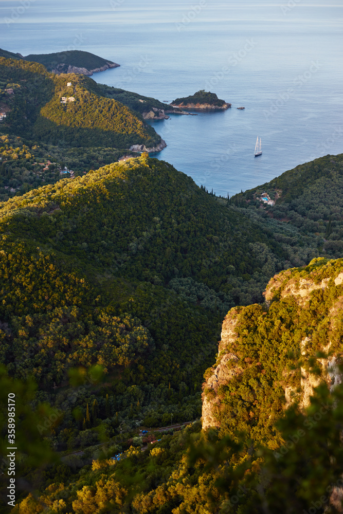 Beautiful panoramic seascape. View of the coastline into the sea bays with crystal clear azure water. Lonely rock with a tree on top, Corfu. Greece.