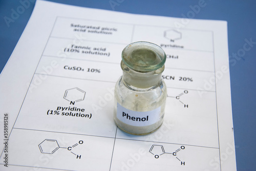 Phenol in old glass bottle on a sheet of paper with chemical formulae (selective focus)