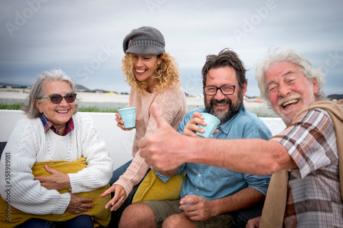 Multi-generation family having fun drinking together outdoor on terrace. Four people from senior to middle age, parents with grandparents