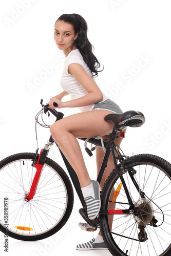 Young woman in sport wear posing on bicycle