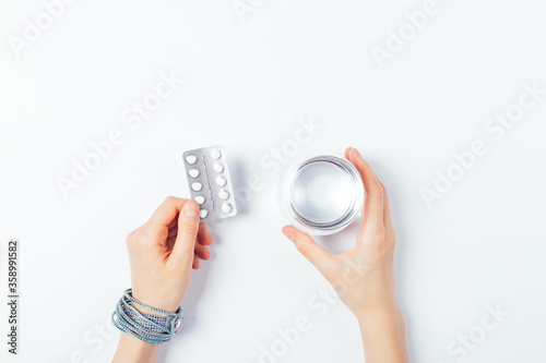 Flat lay female hands holding medical pills and glass of water