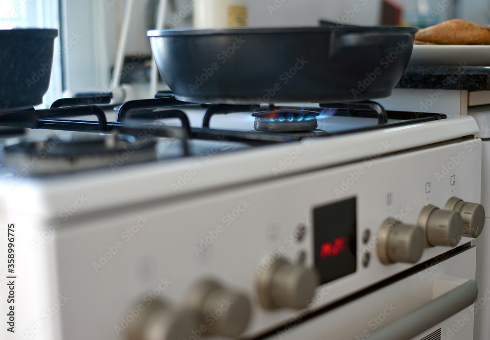 frying pan on a gas stove with a burning burner frying pan on a gas stove with a burning burner