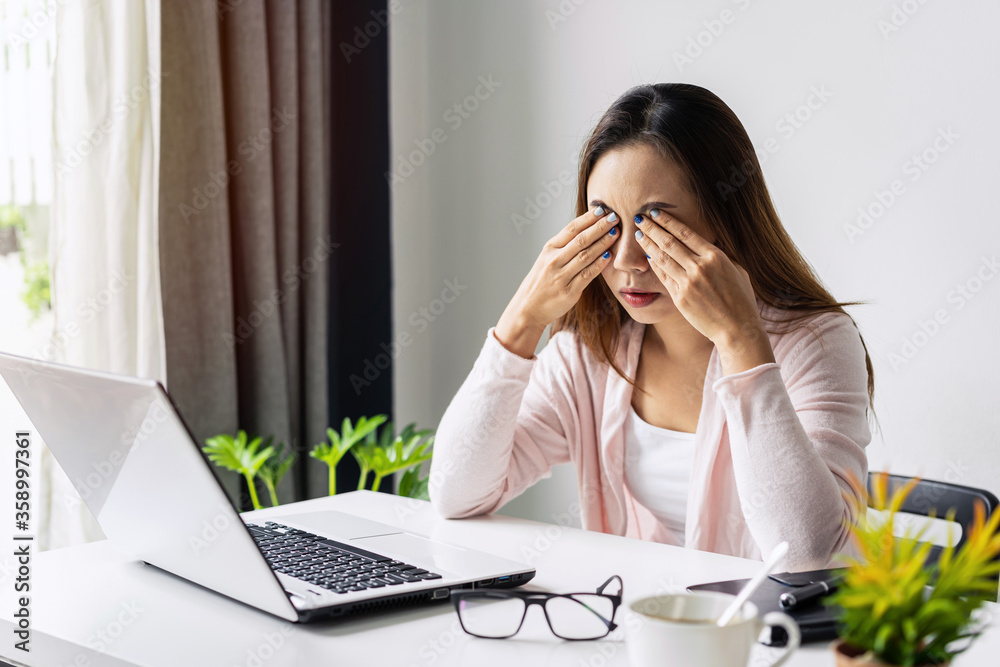 Tired and stressed young asian woman feel pain eyestrain and rubbing her eyes and take off her glasses while sitting at her working place Tired and stressed young asian woman feel pain eyestrain and rubbing her eyes and take off her glasses while sitting at her working place