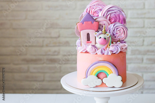 Billede på lærred Cute pink birthday cake for a little girl with fondant unicorn, gingerbread princess castle, rainbow and meringue