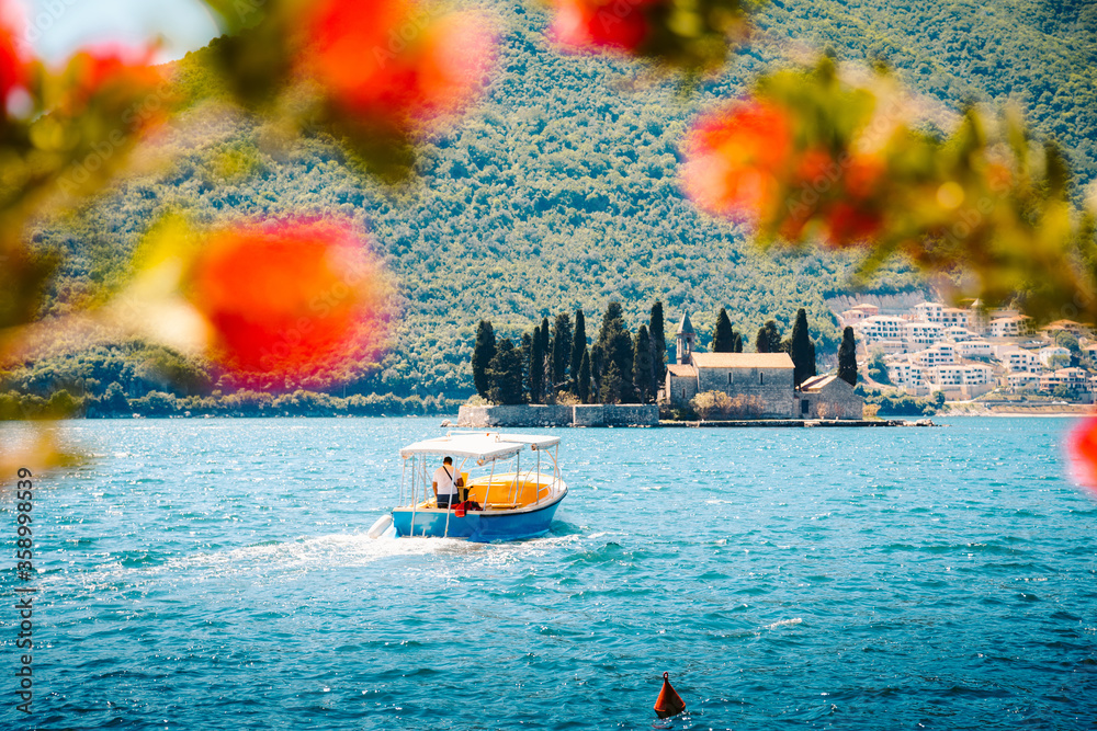 Sightseeing boat with famous Sveti Dorde islet at the Bay of Kotor in summer, Perast, Montenegro