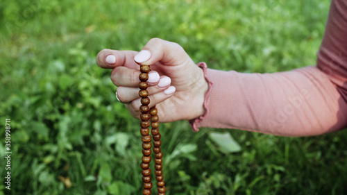 Slika na platnu Woman lit hand close up counts rosary - malas strands of gemstones beads used for keeping count during mantra meditations