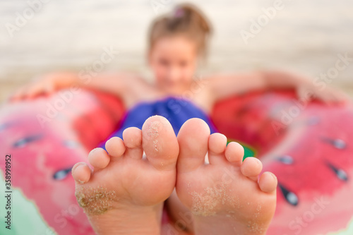 Adorable little girl with large inflatable rubber circle during beach vacation