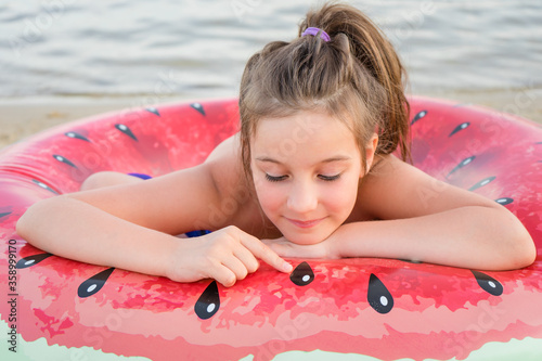 Adorable little girl with large inflatable rubber circle during beach vacation photo