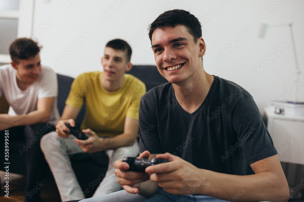 Fototapeta premium teenager boys having fun playing games on console at home