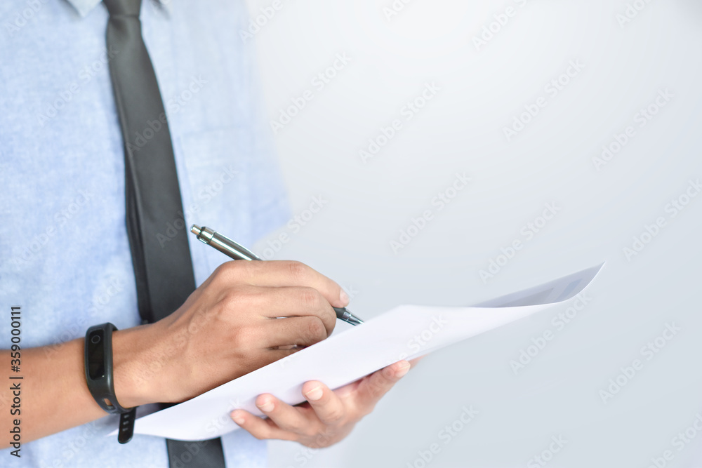 A business man is holding a pen to write on paper, Businessman are analyzing business reports at the office A business man is holding a pen to write on paper, Businessman are analyzing business reports at the office
