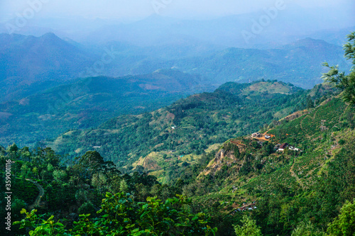 View from above to the green mountains, pathway, smoke and village in Sri Lanka..