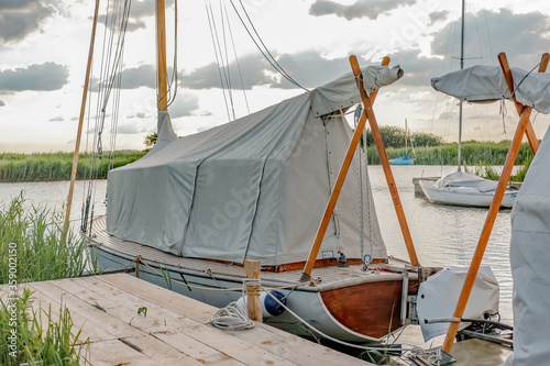  Traditional wooden boat moored up in covers on the River Thurne in the Norfolk Broads National Park on a bright and sunny evening photo