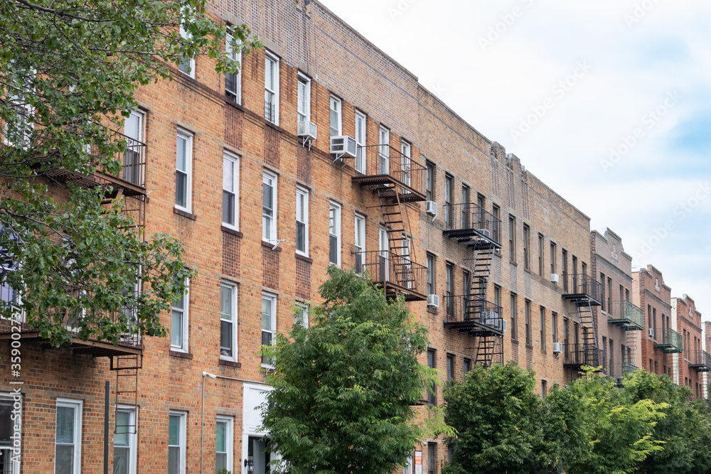 Row of Brick Residential Buildings with Fire Escapes and Green Trees during Spring in Astoria Queens New York