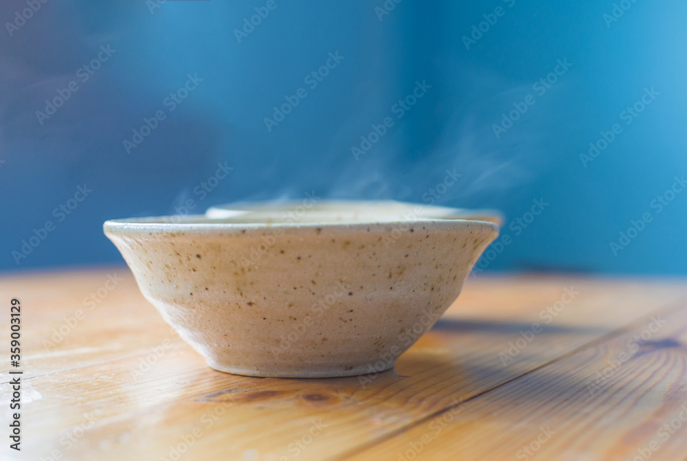 Two ceramic bowls with a hot dish on a wooden table on a blurred background. Two ceramic bowls with a hot dish on a wooden table on a blurred background.